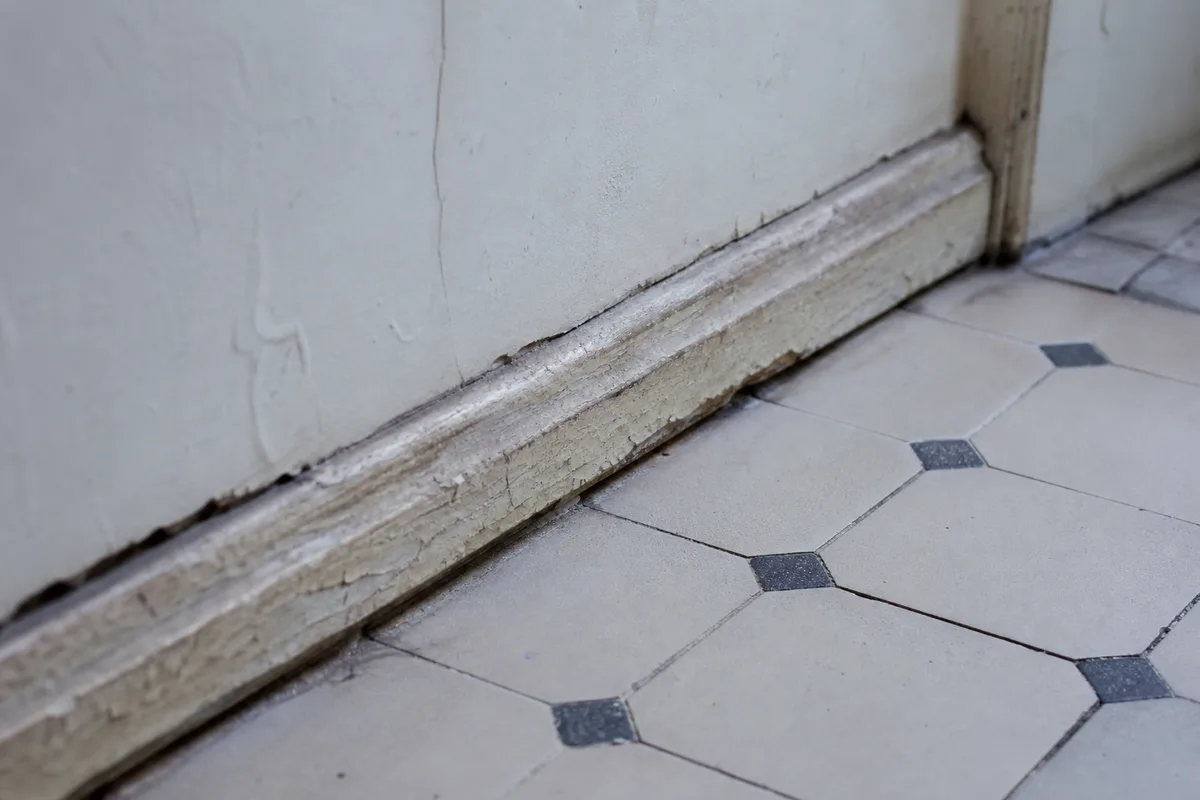 Coin de cuisine ancienne la nuit, plinthes et angle mur-sol en gros plan