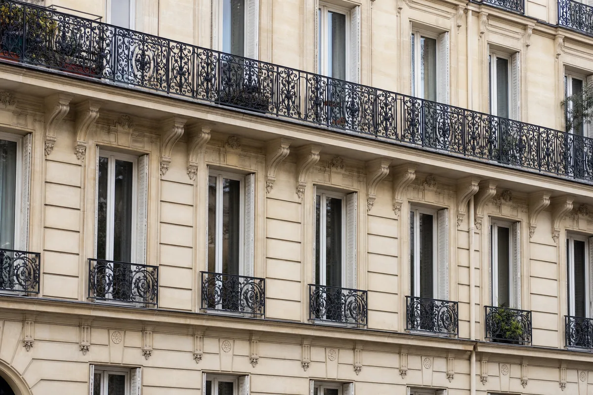 Façade d’un immeuble haussmannien parisien avec balcons en fer forgé